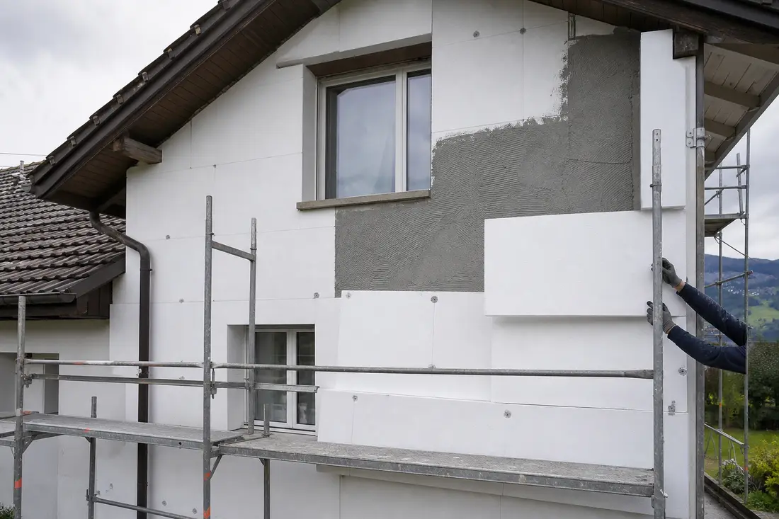 Pose de panneaux isolants sur la façade d'une maison lors d'une isolation par l'extérieur