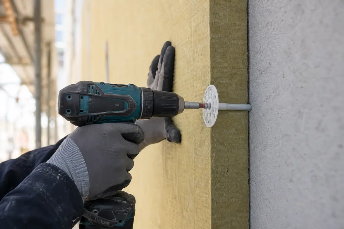 Pose et chevillage de panneaux isolants sur une façade lors d'une isolation par l'extérieur
